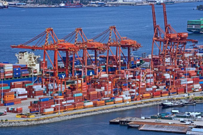Aerial view of a busy container port with stacked shipping containers and cargo cranes